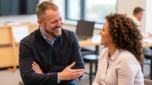 Life Coaching Gespräch: Coach und Klientin lachen entspannt in heller Büroumgebung, persönliche Weiterentwicklung im Fokus
