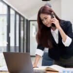 Beautiful attractive young asian businesswoman talking on the phone with her colleague and checking