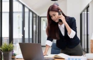 Beautiful attractive young asian businesswoman talking on the phone with her colleague and checking